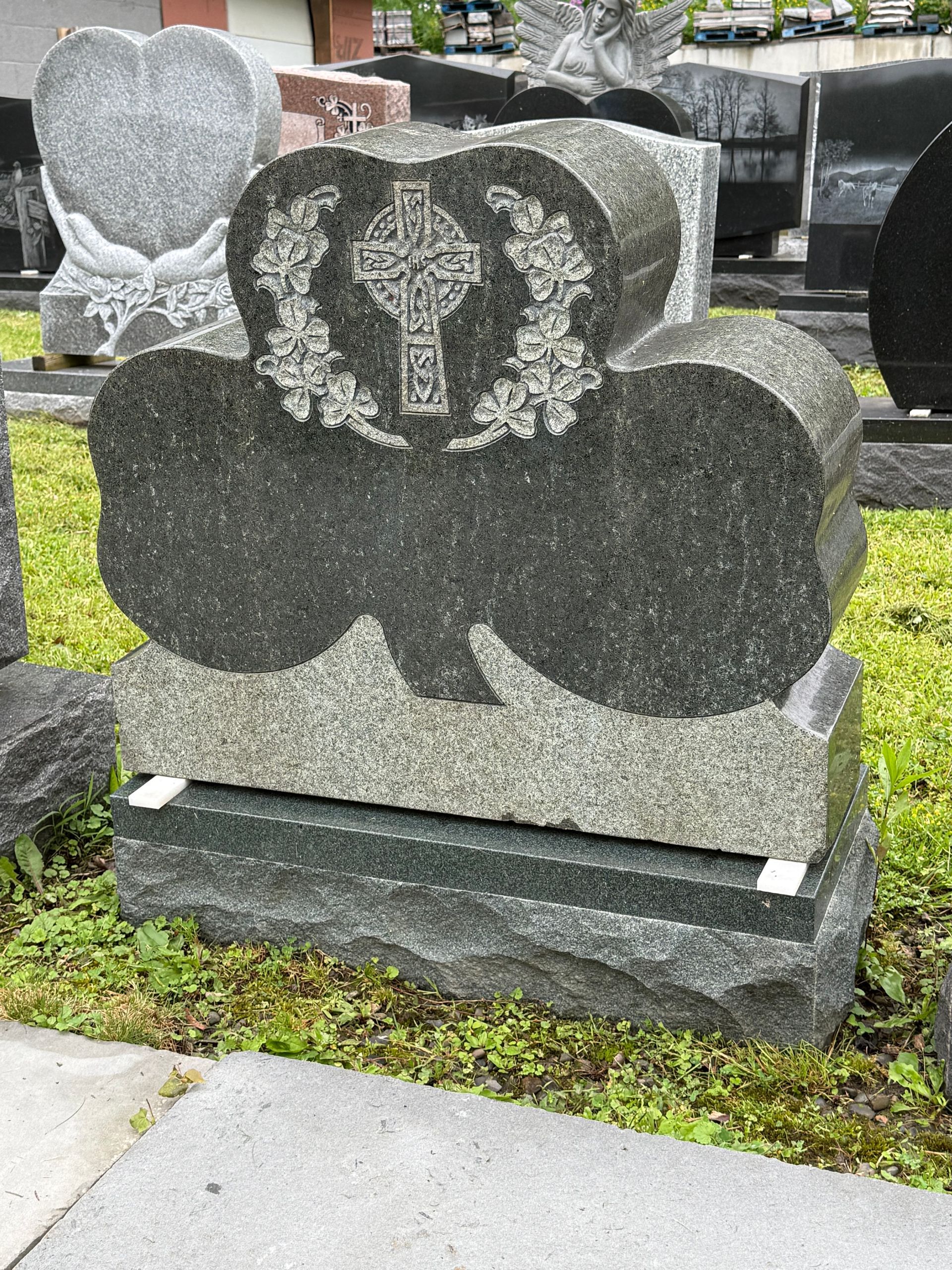 A gravestone with a cross on it is sitting in the grass.
