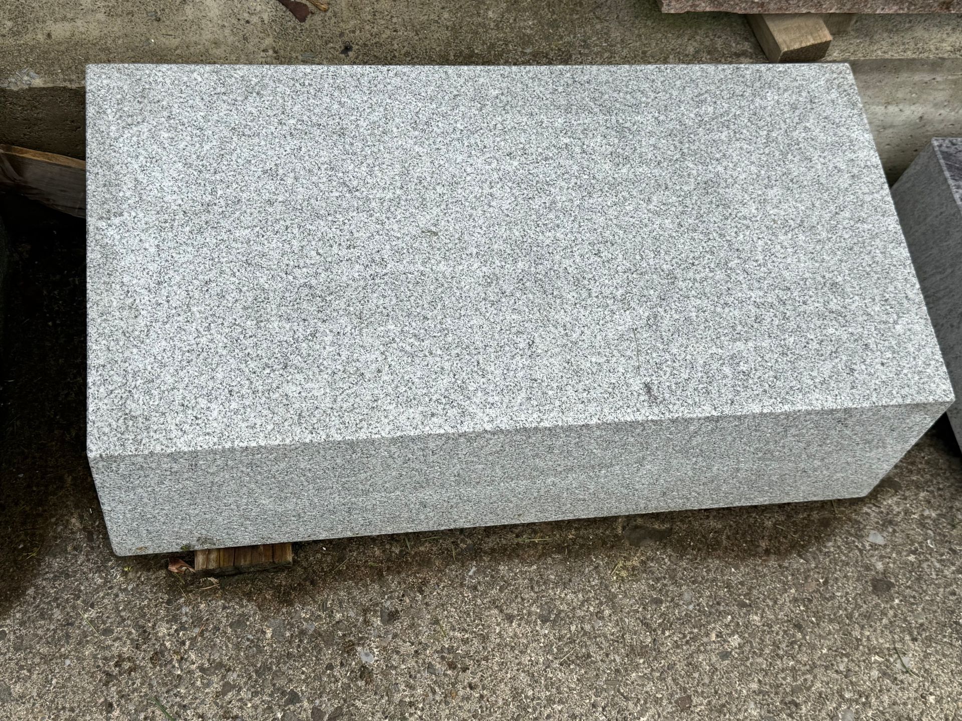 A gray granite block is sitting on top of a concrete surface.