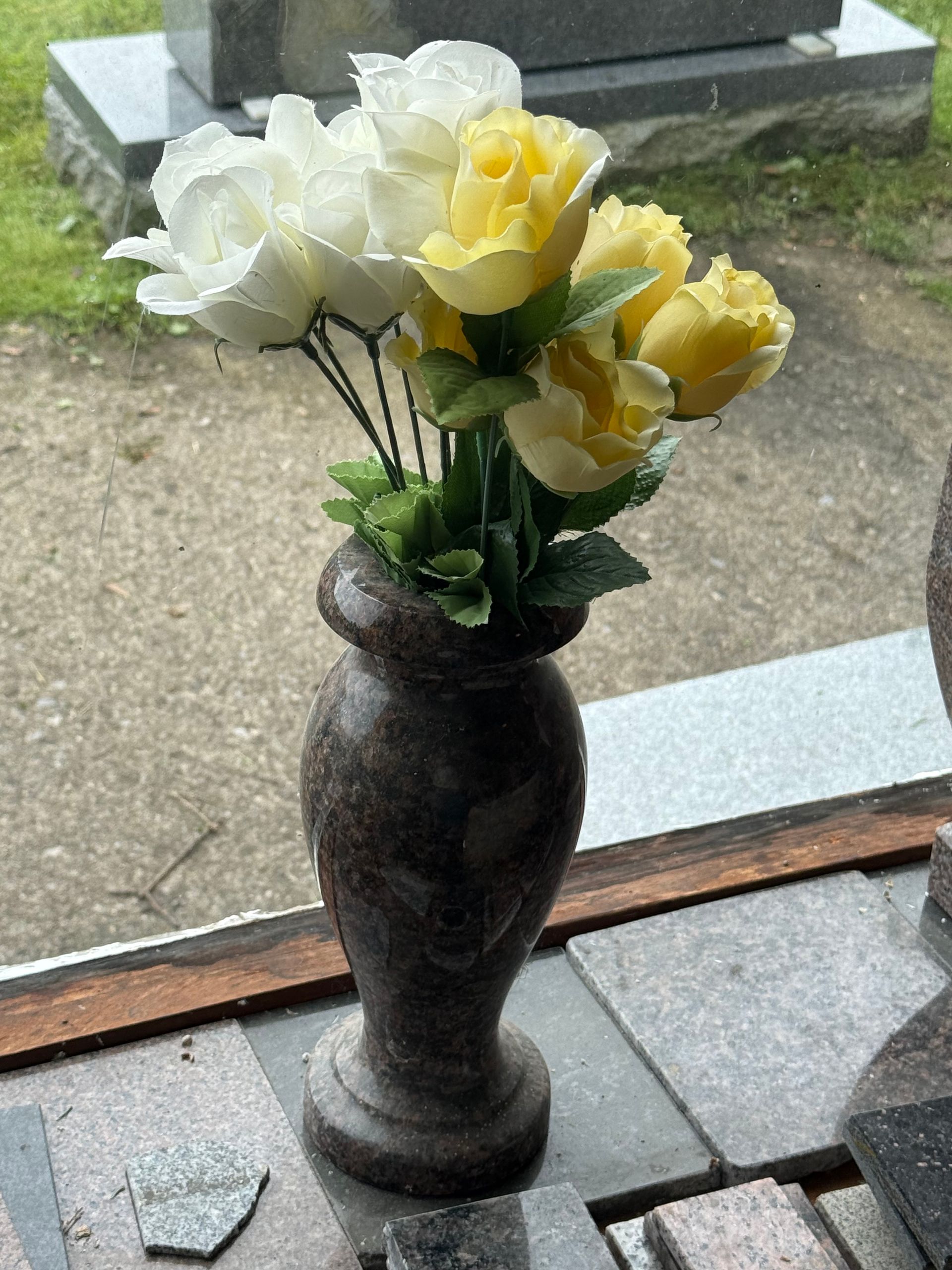 A vase filled with yellow roses and white roses