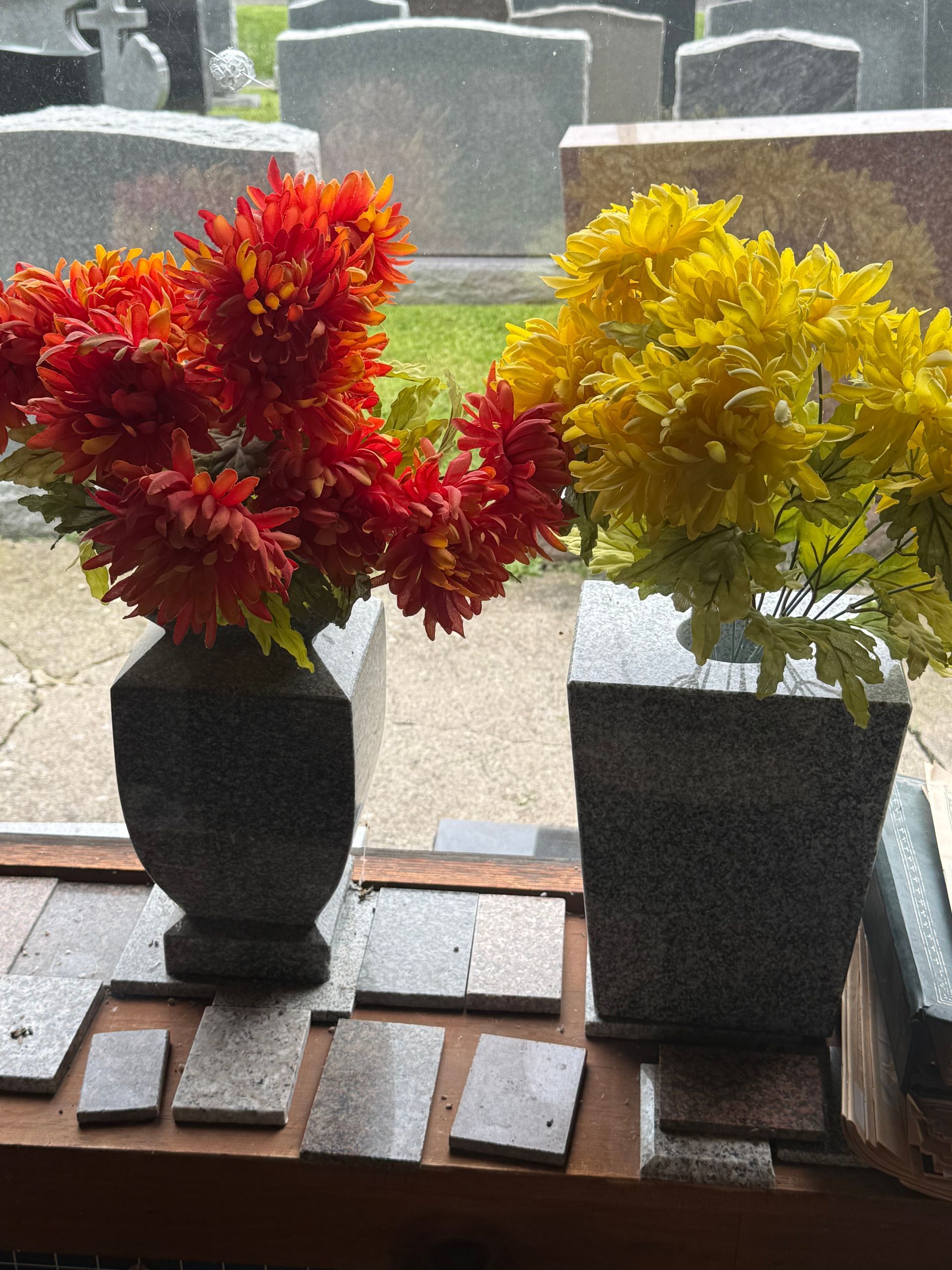 Two vases filled with red and yellow flowers sit on a table