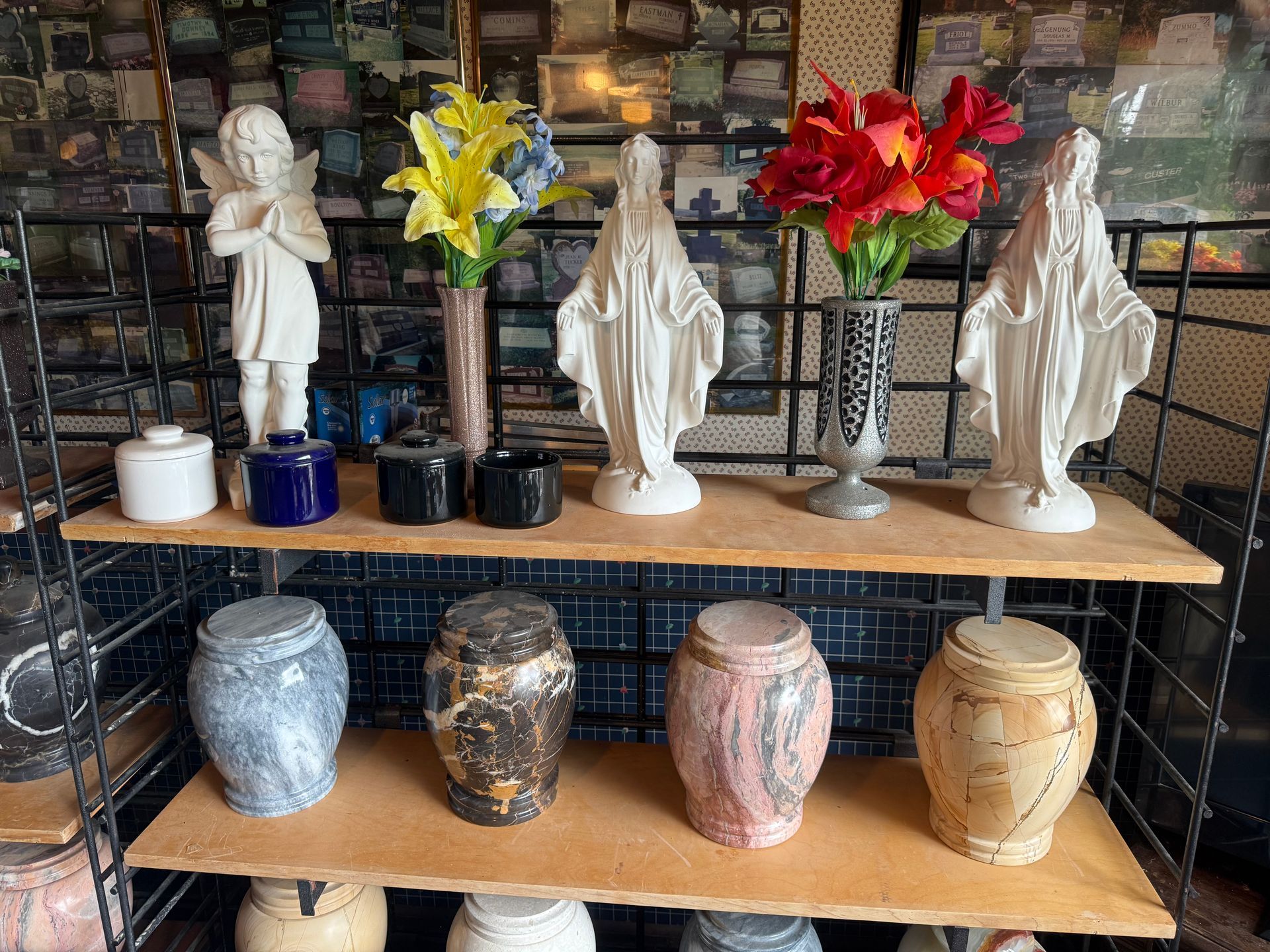 A display of urns and statues on a wooden shelf.