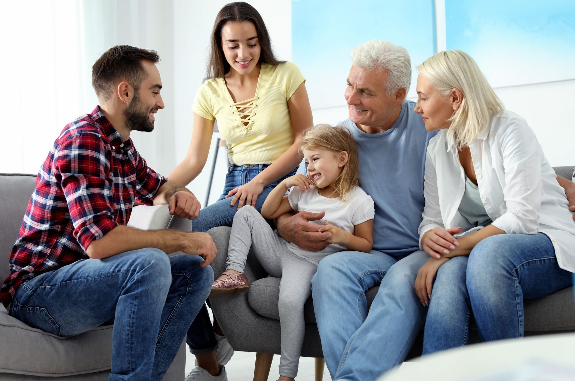Group of diverse people laughing, gathered around a table with food and a laptop in a bright cafe.