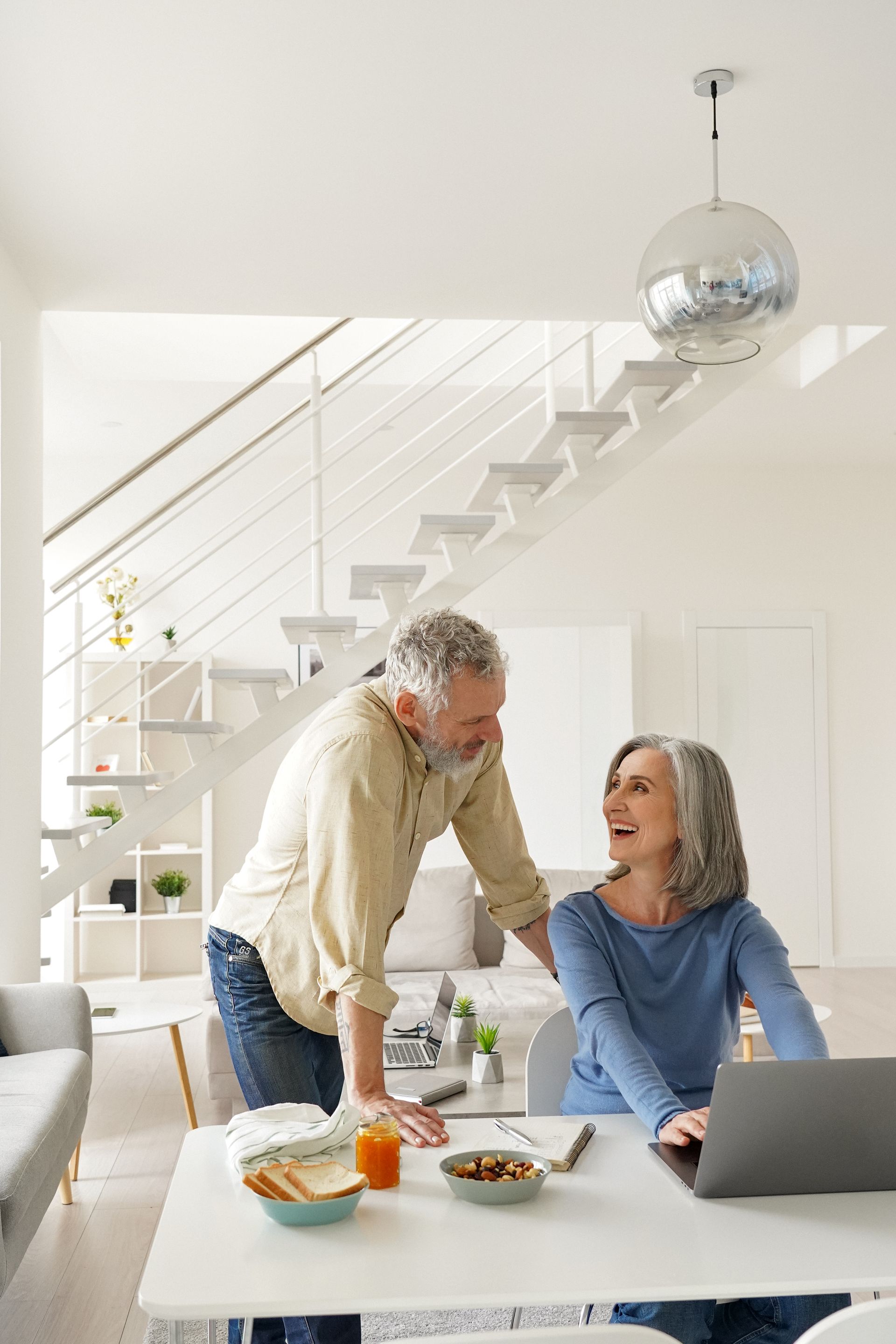 Four diverse professionals smile, gathered around a table indoors, with a tablet and coffee cup.