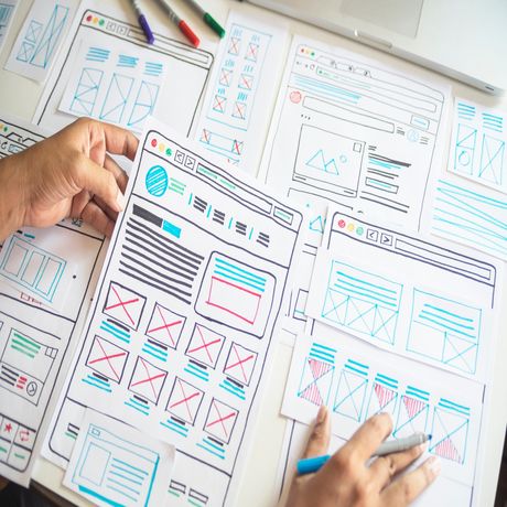 UI/UX designer sketching out a new page on paper using color markers to show each section