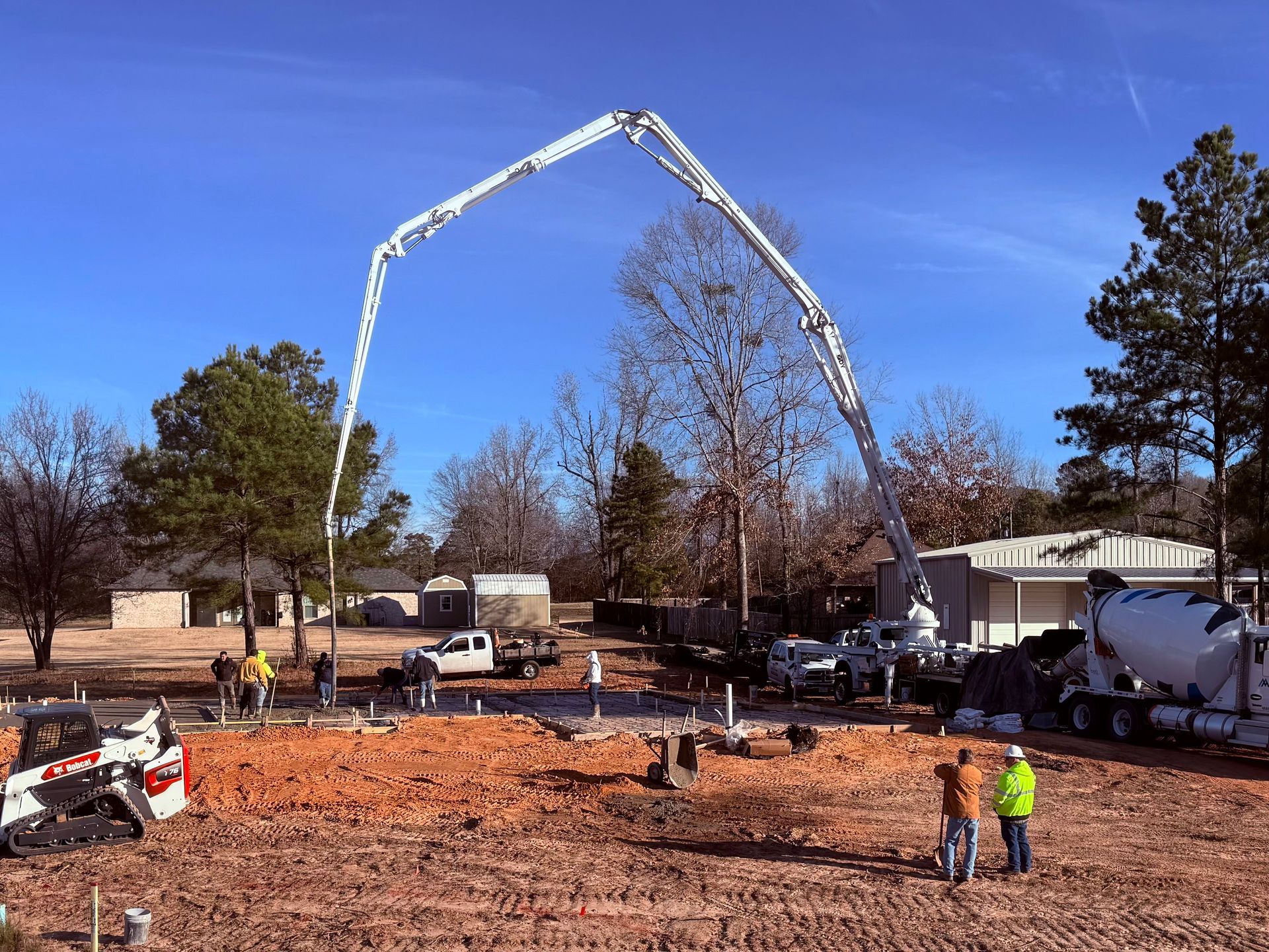 A concrete pump is being used to pour concrete into a dirt field.