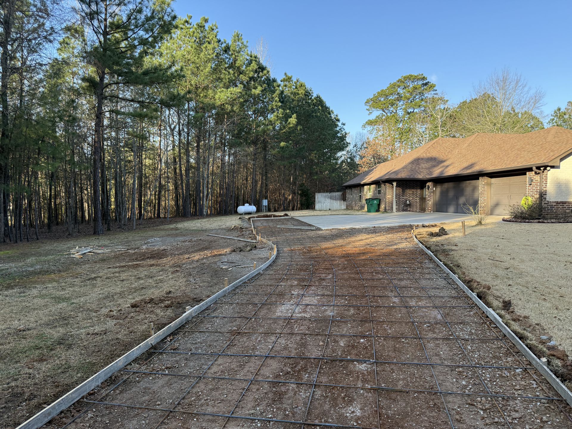 A brick driveway leading to a house in the woods.