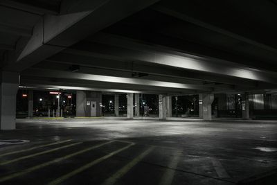 A black and white photo of an empty parking garage at night.