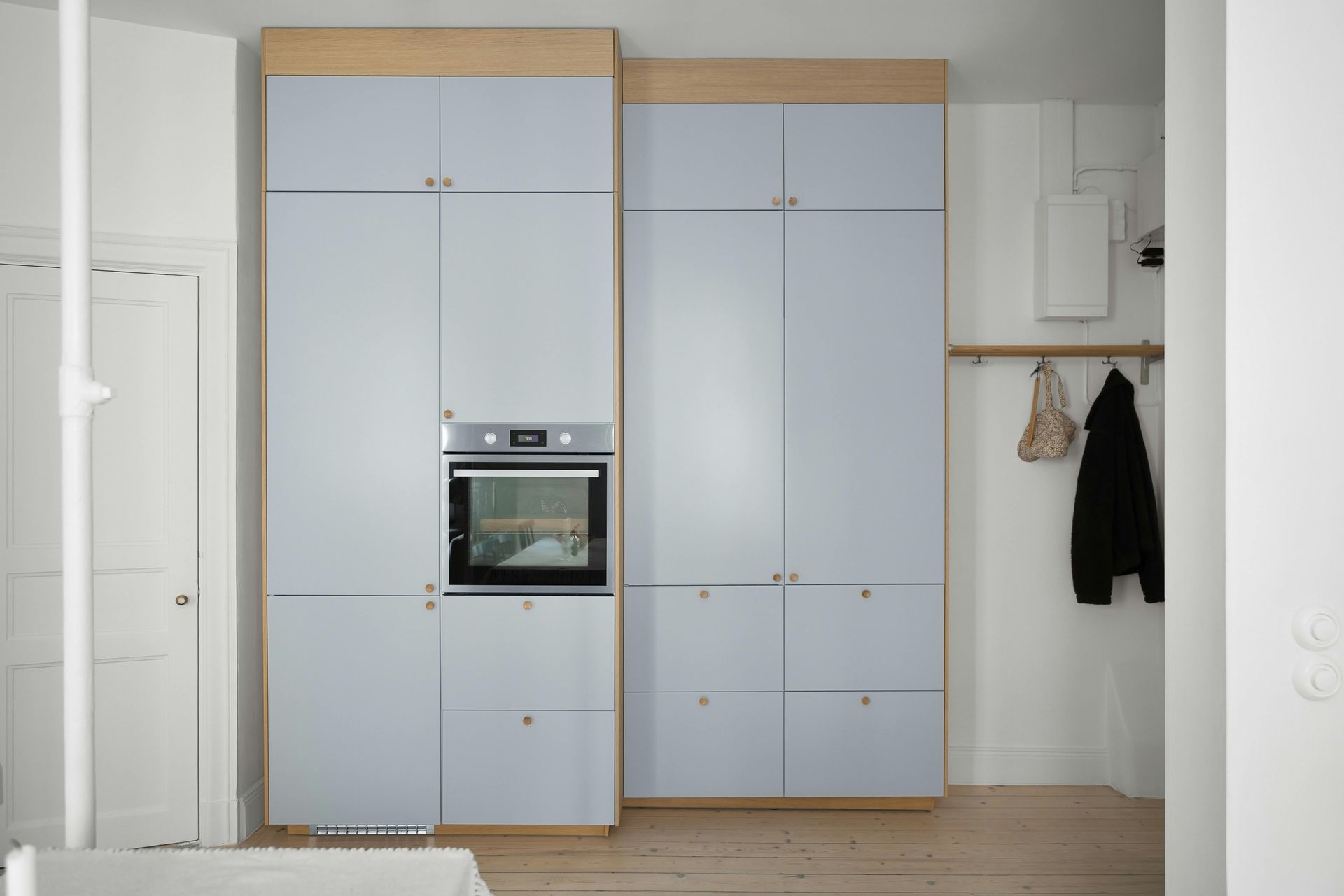 Tall, light blue kitchen cabinets with a built-in oven and drawers against a white wall.