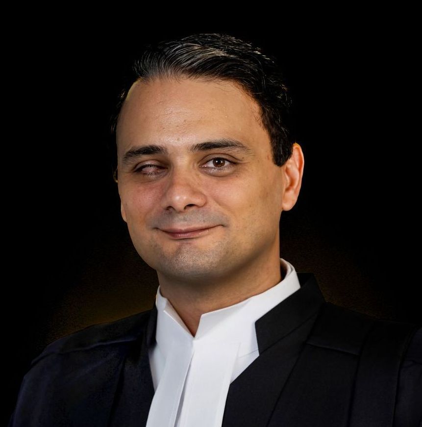 A man in a black suit and white tie is smiling for the camera.