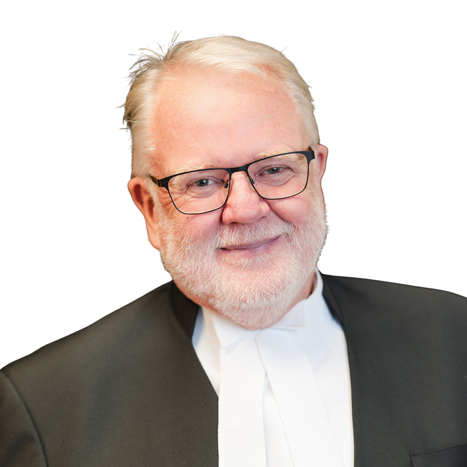 A man wearing glasses and a tuxedo is smiling for the camera.