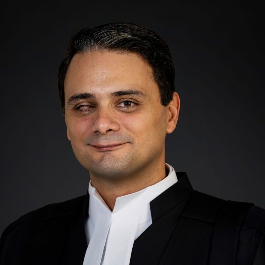 A man in a black suit and white tie is smiling for the camera.