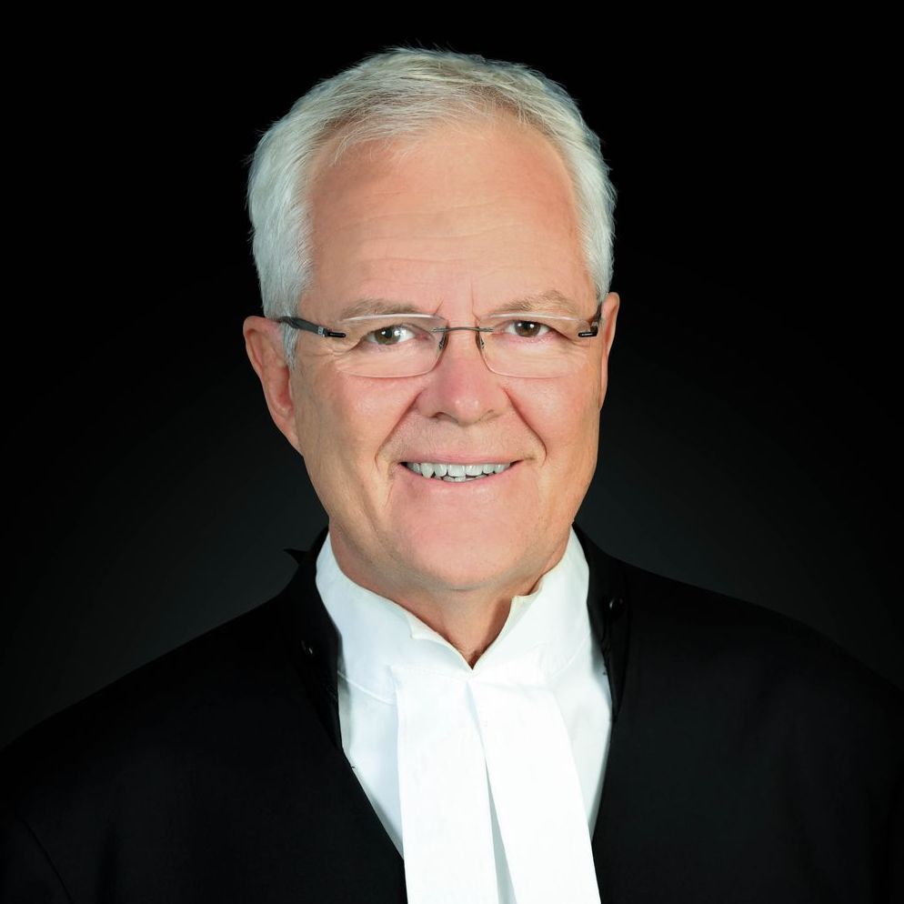 A man wearing glasses and a tuxedo is smiling for the camera.