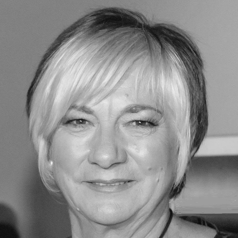 A woman with short blonde hair is smiling in a black and white photo.