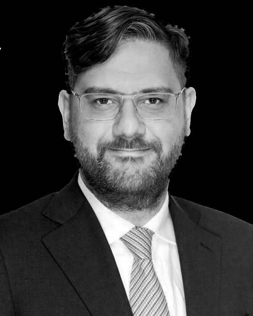 A man with a beard and glasses is wearing a suit and tie.