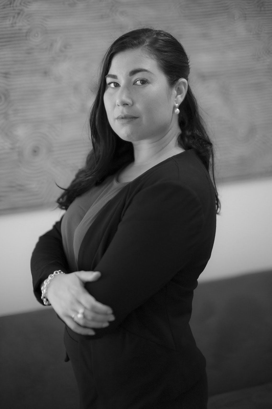 A black and white photo of a woman standing with her arms crossed.