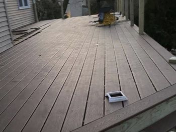 A person is working on a wooden deck with a circular saw.