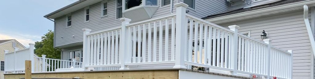 A white house with a white railing and a wooden deck.