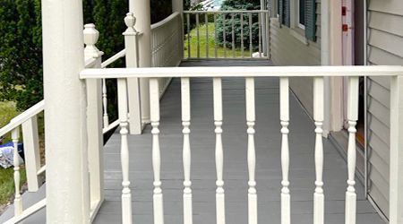 A porch with a white railing and stairs leading up to it.