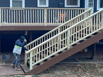 A man is standing on a set of stairs leading up to a deck.