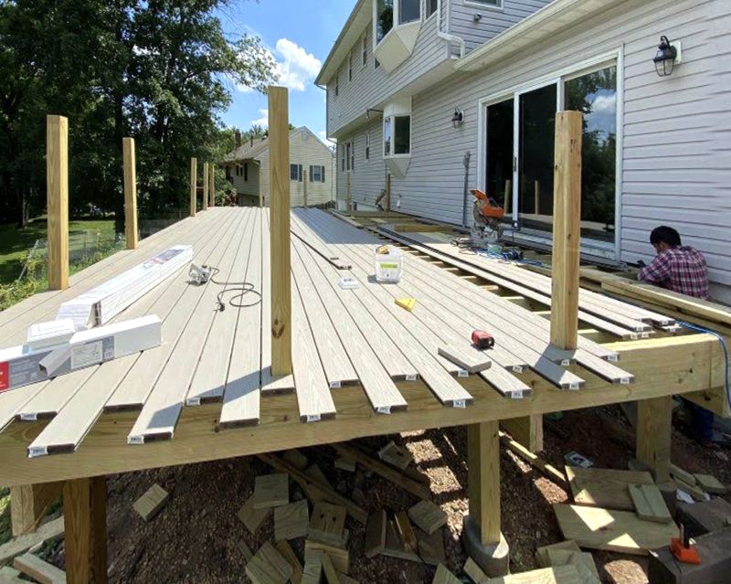 A wooden deck is being built in front of a house