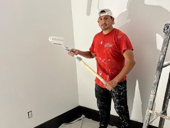 A man in a red shirt is holding a paint roller.