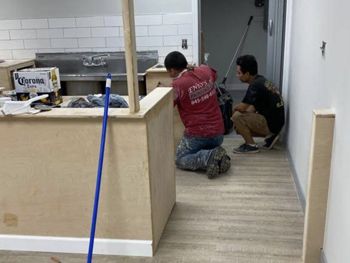 Two men are working on a counter in a kitchen.