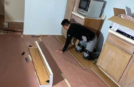 A man is kneeling on the floor in a kitchen.