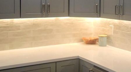A kitchen with gray cabinets and a white counter top.