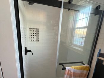 A bathroom with a shower stall and a window.