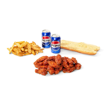 Two pepsi cans are next to a bunch of chicken wings and french fries