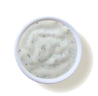 A white bowl filled with ranch dressing on a white background.