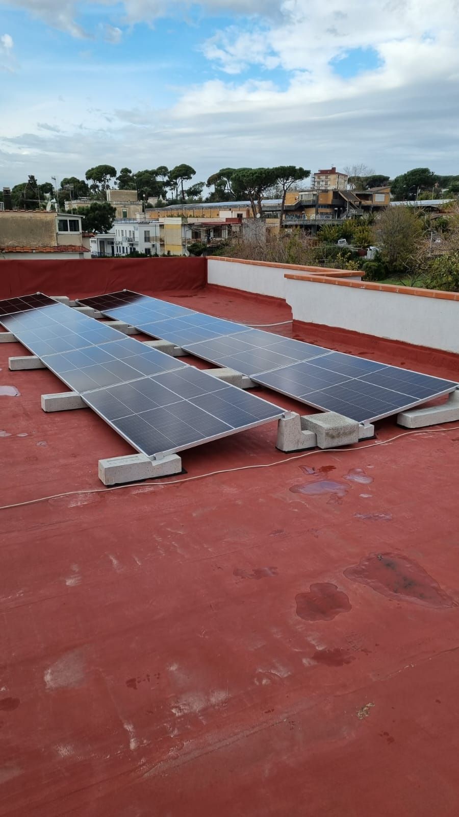 Una fila di pannelli solari posizionati in cima a un tetto rosso.