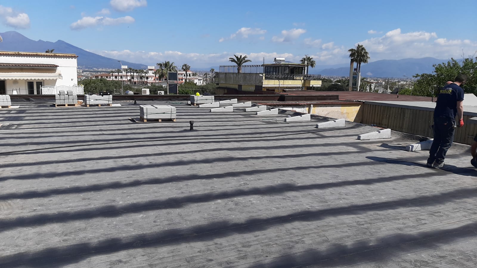 Un uomo con una camicia blu è in piedi su un tetto.