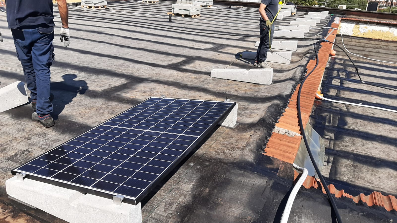 Due uomini stanno installando pannelli solari su un tetto.