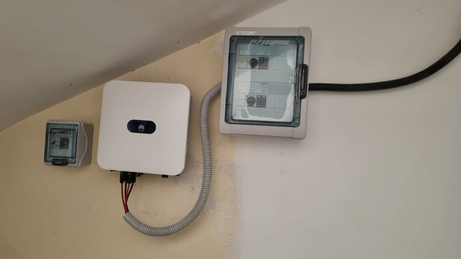 Una scatola bianca è appesa a una parete accanto a un contatore.