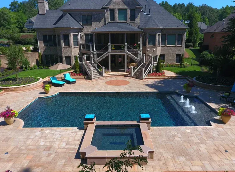 Large brick house with pool, spa, and fountain in a landscaped backyard.