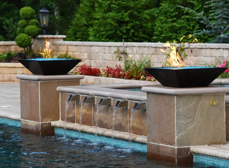 Fire bowls atop stone pillars with water cascading into a pool.