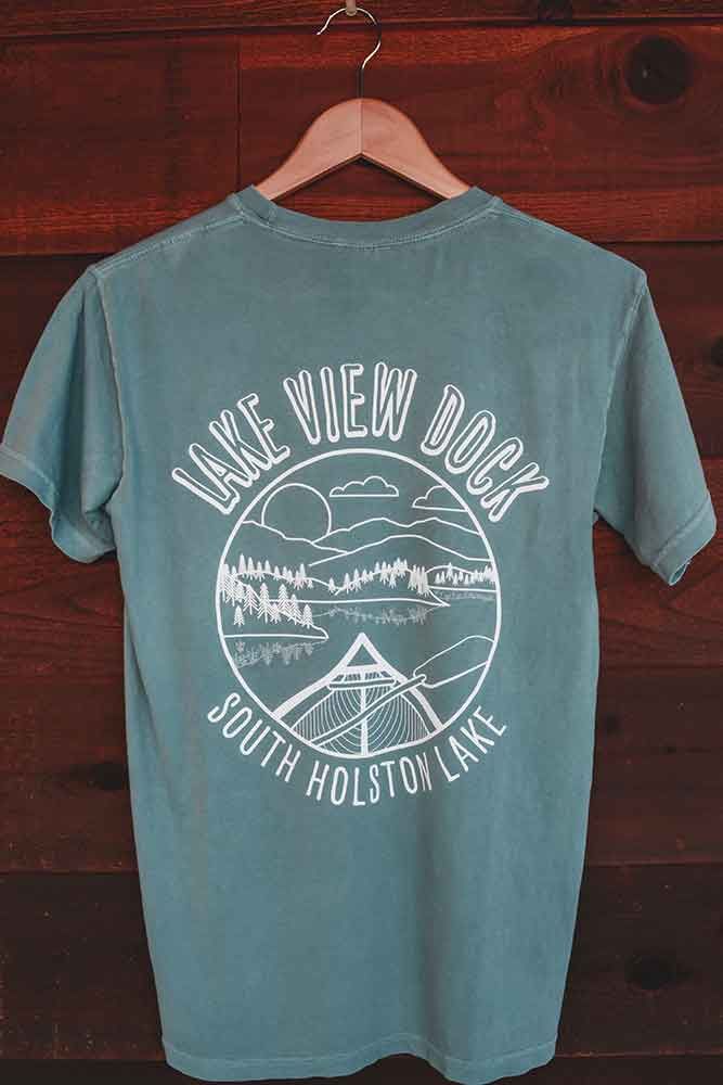 A green t-shirt is hanging on a wooden hanger.