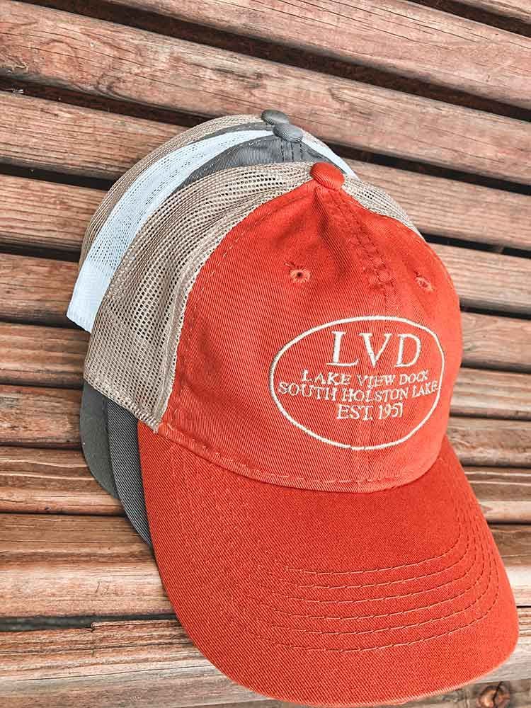 Three baseball caps are stacked on top of each other on a wooden table.