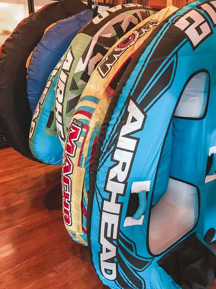 A bunch of inflatable tubes are stacked on top of each other on a wooden floor.