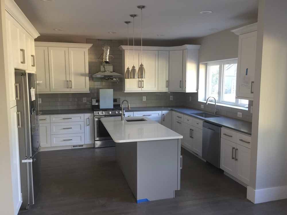 A kitchen with white cabinets , stainless steel appliances , and a large island.