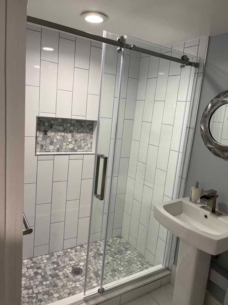 A bathroom with a sliding glass shower door , sink and mirror.