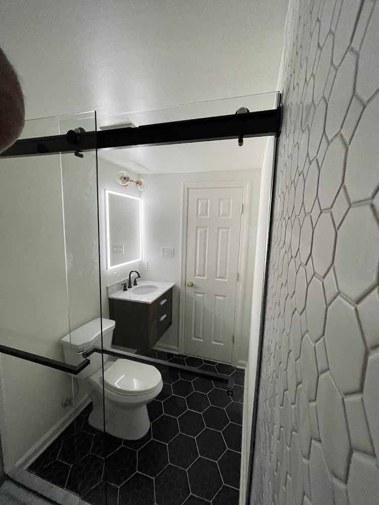 A bathroom with a toilet , sink and mirror.