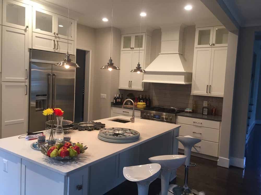 A kitchen with white cabinets , stainless steel appliances and a large island.