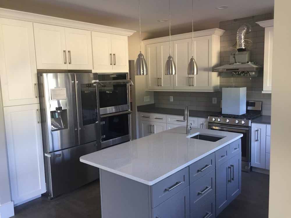 A kitchen with white cabinets , stainless steel appliances , and a large island.