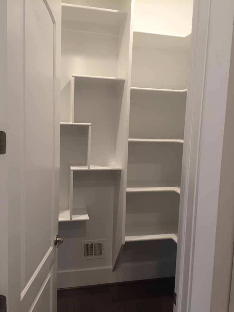 A walk in closet with lots of shelves and a door.