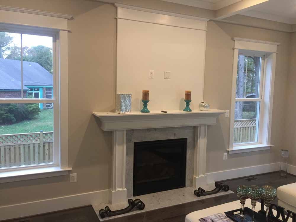 A living room with a fireplace and two windows.