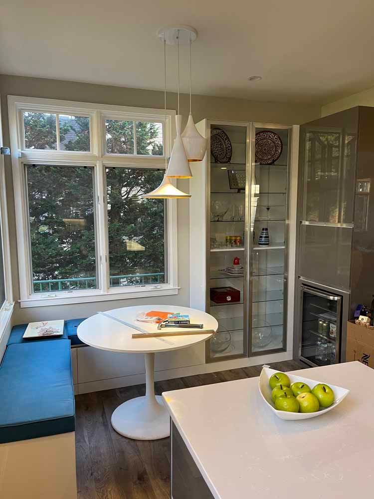 A kitchen with a table and a bowl of apples on the counter.