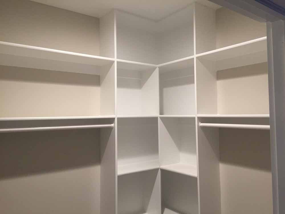A walk in closet with lots of shelves and hanging clothes.
