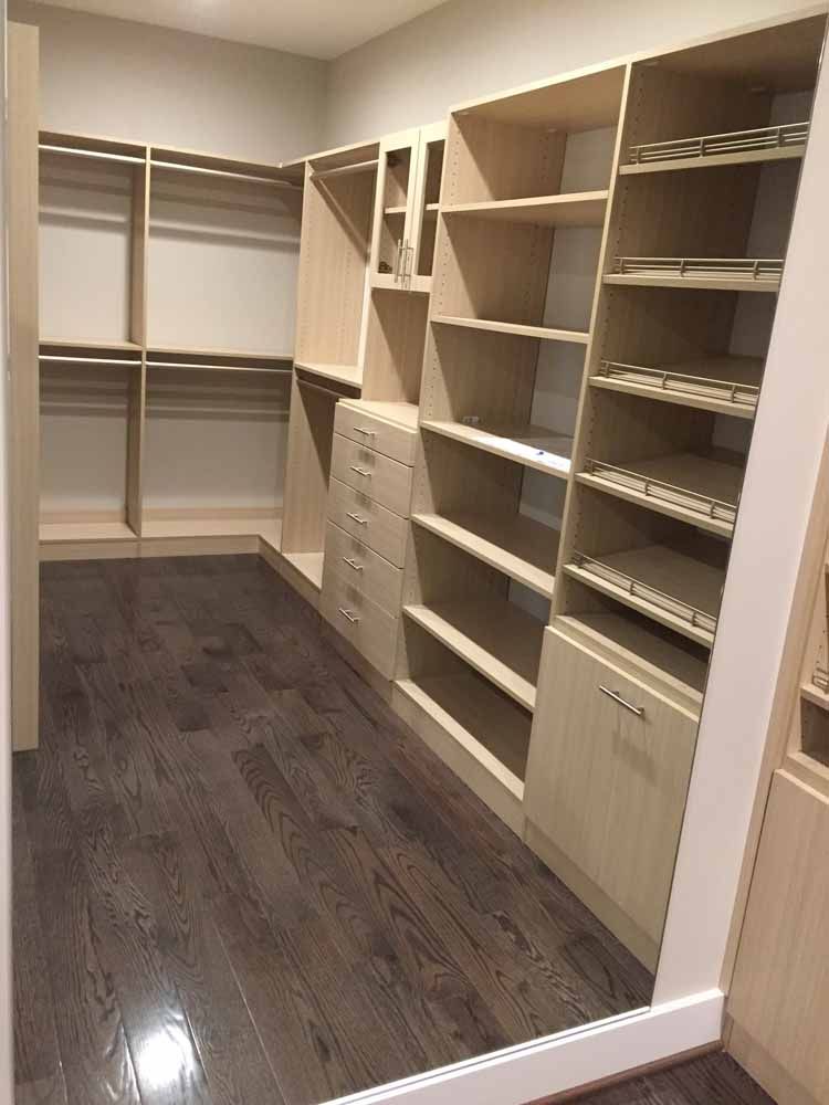 A walk in closet with lots of shelves and drawers and a mirror.